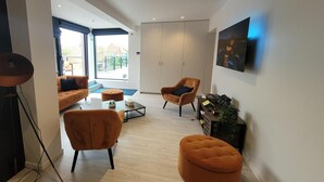 A modern living room with a sofa, two armchairs, a coffee table, and a television on the wall. - Apartment in Zuienkerke with Terrace (zuienkerke)