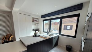 A modern kitchen with a large window, dark cabinetry, and a white countertop. - Apartment in Zuienkerke with Terrace (zuienkerke)