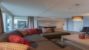 A modern living room with a sectional sofa, a coffee table, and a fireplace. - Holiday Home in Colijnsplaat (Colijnsplaat)