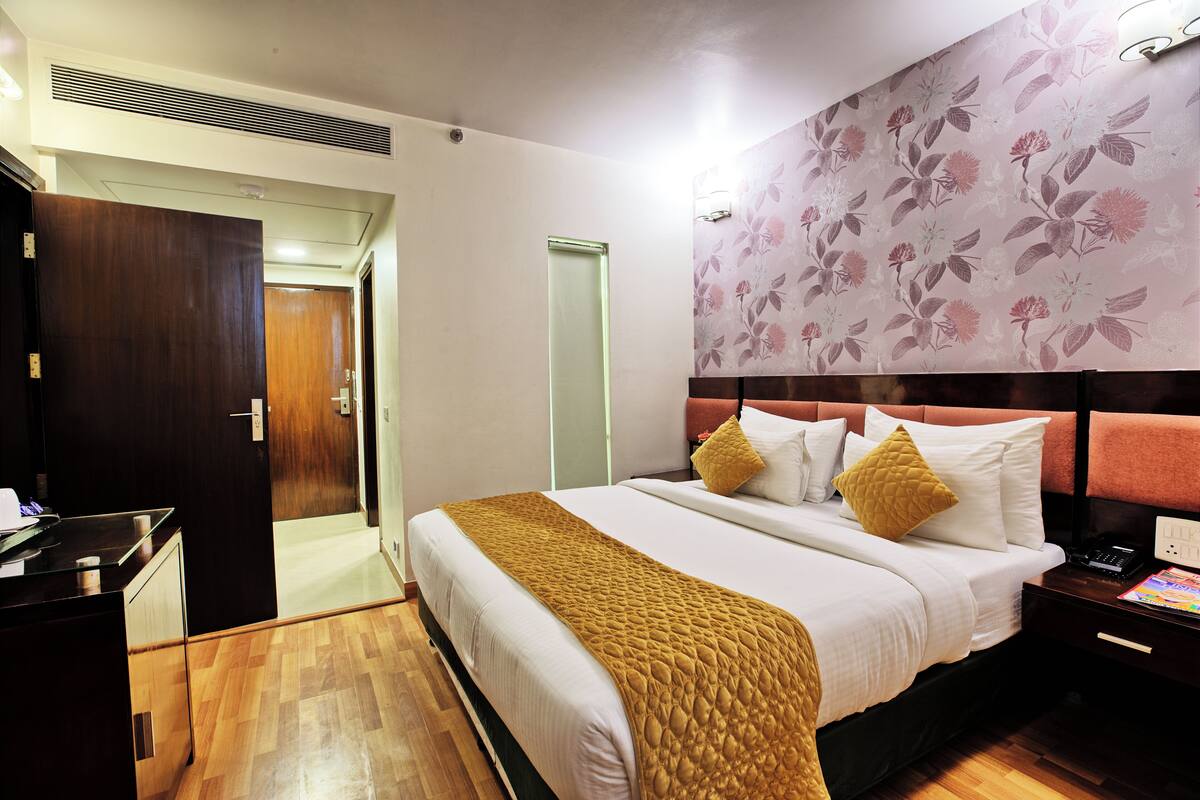 A hotel room with a bed, bedside table, and a wardrobe.