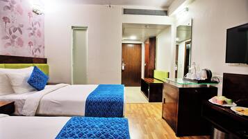 A hotel room with two beds, a desk, a mirror, and a television.