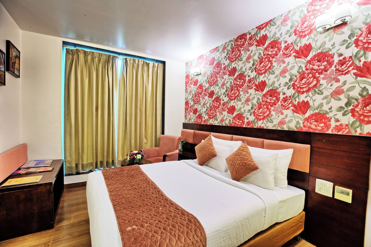 A hotel room with a bed, a desk, a chair, and a window with curtains.