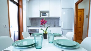 A dining area with a white table set for four, green plates, and clear glassware. - Belvilla by OYO Apartment in Arona (Arona)