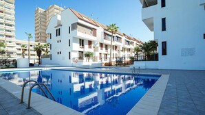 A swimming pool with a clear blue water surface, surrounded by a tiled deck. - Belvilla by OYO Apartment in Arona (Arona)