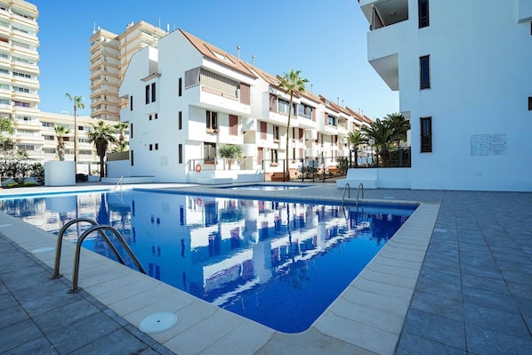 A swimming pool with a clear blue water surface, surrounded by a tiled deck.