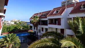 A multi-story building with red-tiled roofs, balconies, and a swimming pool. - Belvilla by OYO Apartment in Arona (Arona)