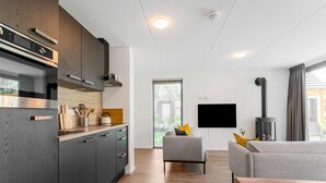 Una cocina moderna con armarios de madera oscura, electrodomésticos de acero inoxidable y un comedor con mesa de madera y sofá gris.
