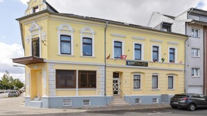 A yellow building with a sign reading "KISPET HOTEL" and a staircase leading to the entrance. - Apartment in Oberhausen near Lake & River (Oberhausen)