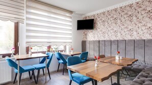A modern dining area with a wooden table, blue upholstered chairs, and a grey cushioned bench. - Apartment in Oberhausen near Lake & River (Oberhausen)