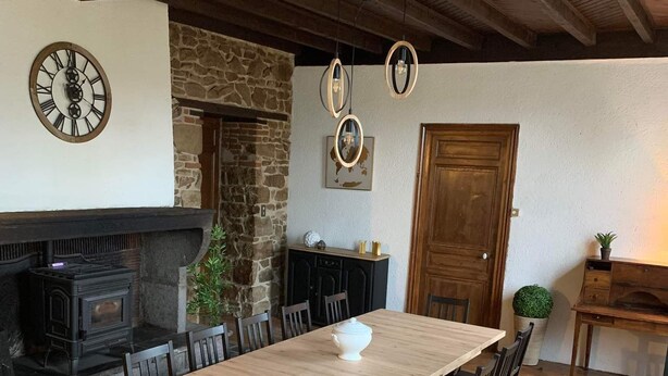 Un comedor rústico con una larga mesa de madera y sillas, una chimenea de piedra y techo de madera.