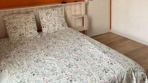 Un dormitorio con cama, mesita de noche, lámpara, una puerta y adornos en la pared.