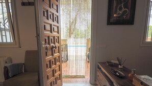 A wooden door with a grid pattern, a chair, a wooden dresser, and a framed artwork on the wall. - Simba Apartment by Hello Homes Sitges (Sitges)