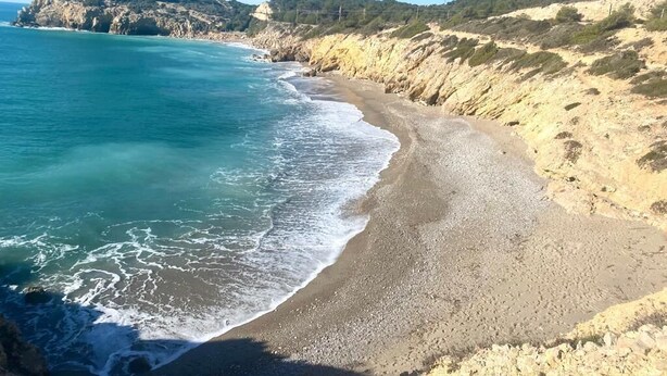 A coastal landscape with a sandy beach, rocky cliffs, and a clear blue sea. - Simba Apartment by Hello Homes Sitges (Sitges)