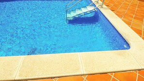 A rectangular swimming pool with clear blue water, surrounded by orange-tiled steps and a metal ladder. - Simba Apartment by Hello Homes Sitges (Sitges)