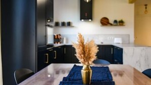 A modern kitchen with dark cabinetry, a marble countertop, and a vase with dried flowers on the table. - Ein Strand- und Seehaus. 200m von der Camminer Bucht,1,8km vom Meer Entfernt (Zastań)