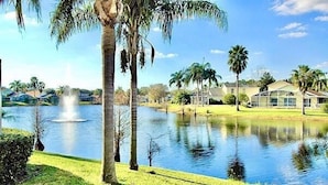 A serene lakeside view with a fountain, palm trees, and houses in the background. - Ref 417.  Stunning villa in perfect location Close to Disney (Four Corners)