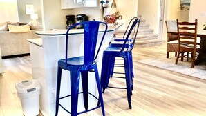 A modern kitchen with blue bar stools, a white trash bin, and a dining area with a wooden table and chairs. - Ref 417.  Stunning villa in perfect location Close to Disney (Four Corners)