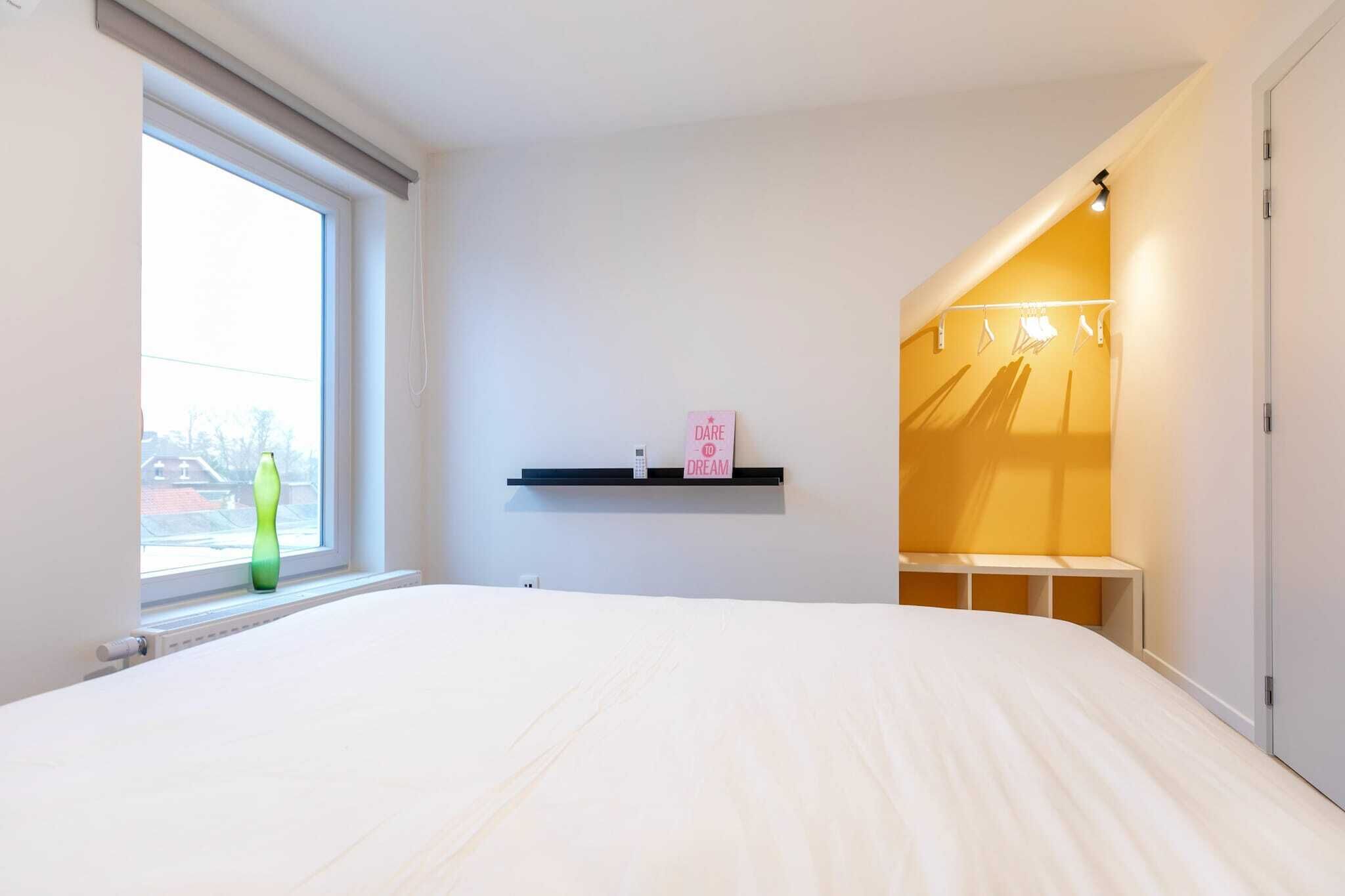 Een slaapkamer met een groot bed, een raam, een plank met een bord en een kledingkast.