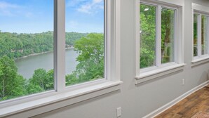 Una habitación con amplios ventanales que dan a un lago y un bosque.