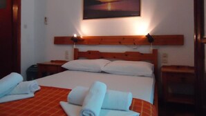 Ein Hotelzimmer mit Bett, einem Sonnenuntergangsbild und einem Holzkopfbrett.