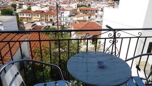 Ein Balkon mit einem runden Tisch und zwei Stühlen, mit Blick auf ein dicht bebautes Wohngebiet mit roten Ziegeldächern.