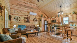A rustic cabin interior with a living room, kitchen, and dining area.