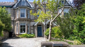 A historic stone building with a prominent entrance, a gravel driveway, and a sign indicating the name 'HILLCOTE'. - Boutique Family Home, Garden, Parking 3 cars, 2 Living Rooms. Cornwall (Wadebridge)