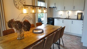Una cocina moderna con armarios blancos, una mesa de comedor de madera y un gran reloj de pared.