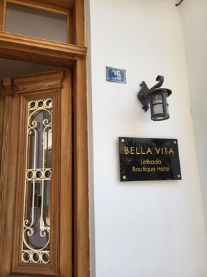 A wooden door with ornate metalwork, a wall-mounted sign for 'Bella Vita Boutique Hotel', and a small blue sign with the number 25. - Bella Vita Boutique Hotel Lefkada (Lefkada)