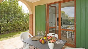 A patio with a table set for two, featuring a fruit bowl, wine glasses, and a vase with flowers. - Casa Monte Cicogna PT 1 by Wonderful Italy (Moniga del Garda)