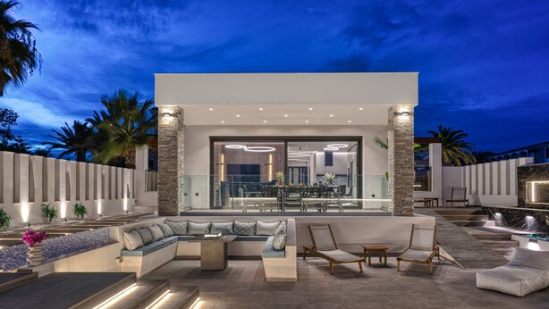 Un espacio exterior moderno con una zona de estar integrada, sofás y una zona de comedor.
