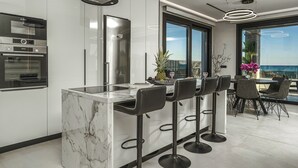 Una cocina moderna con una isla de mármol, electrodomésticos de acero inoxidable y una zona de bar con taburetes.