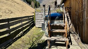 Un espace extérieur en bois doté d’une structure métallique, d’une clôture en bois et offrant une vue sur les montagnes en arrière-plan.