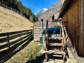 A wooden outdoor area with a metal structure, a wooden fence, and a mountain backdrop. - Alpine Holiday Home in Lungau (Vordermuhr)