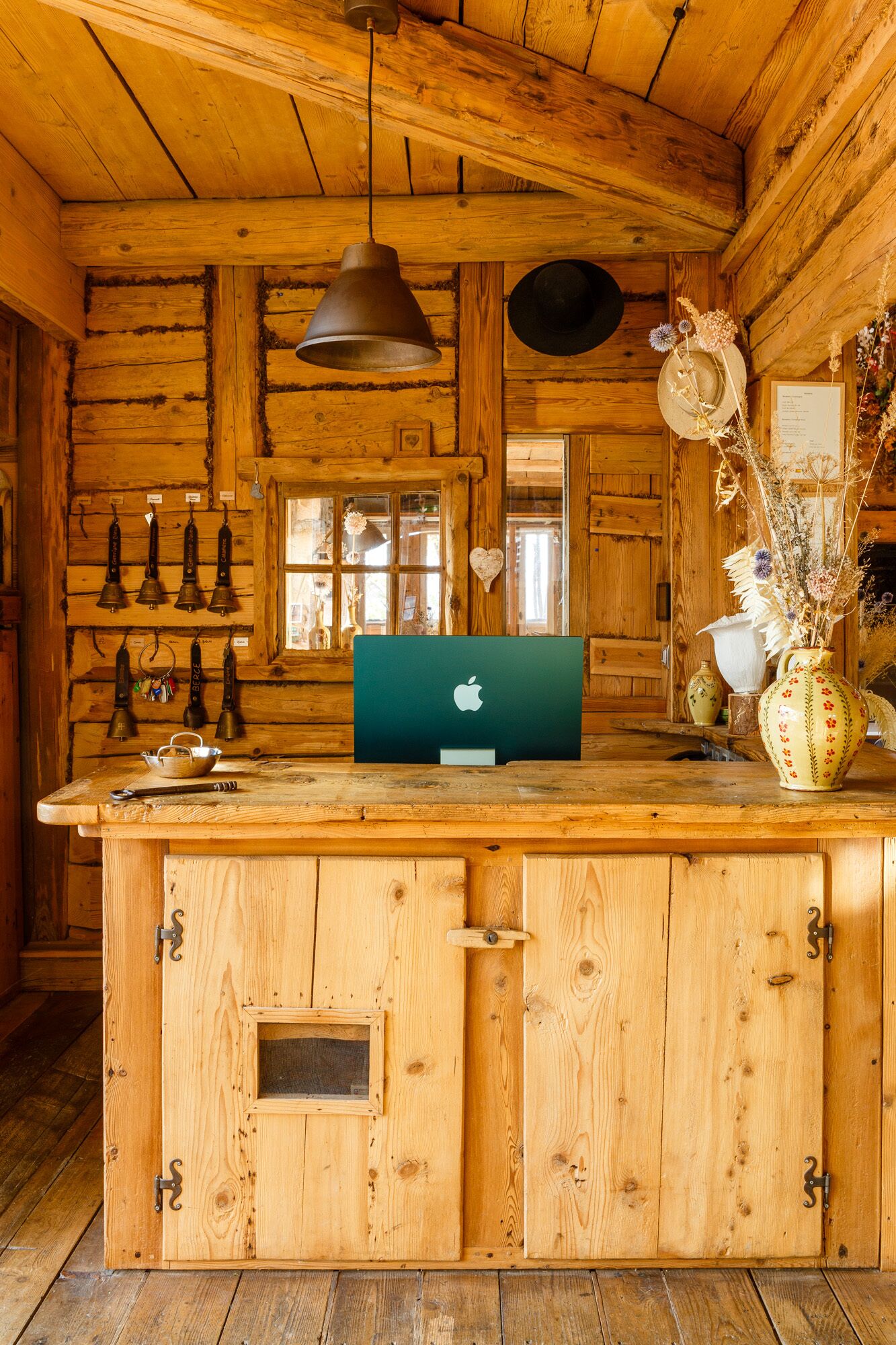 A rustic wooden cabin interior with a wooden bar counter, a laptop, and various decorative items.
