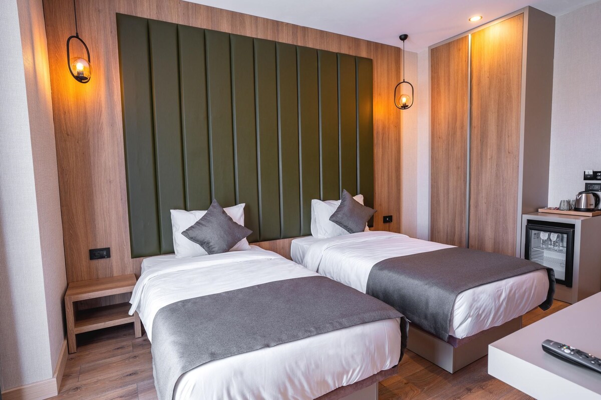 A hotel room with two beds, a small kitchenette, and a television.