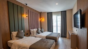 A hotel room with two beds, a TV, a desk, and a window with curtains. - Perast City Hotel (Konyaalti)