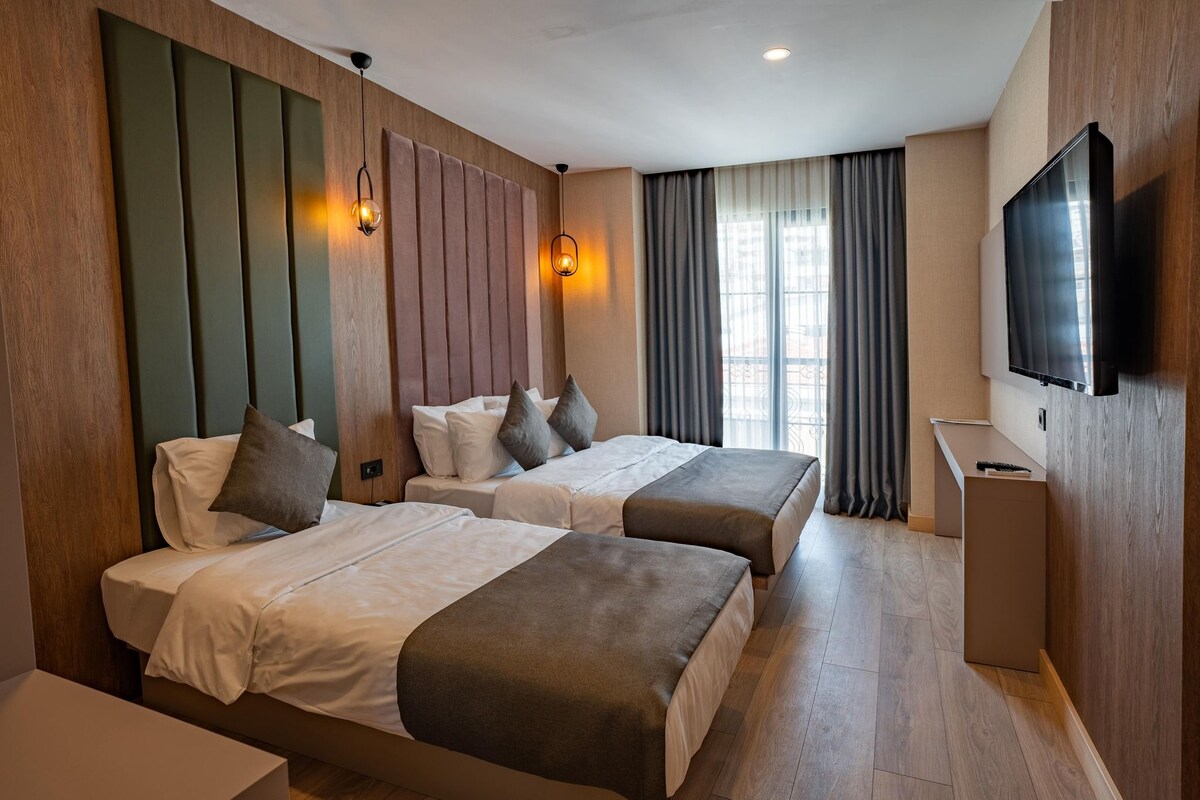 A hotel room with two beds, a TV, and a desk.