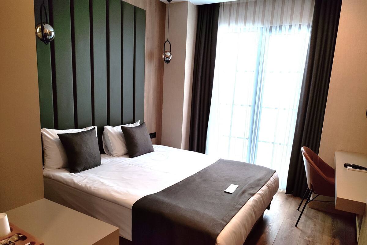 Une chambre d’hôtel comprenant un lit, une table de chevet et un bureau avec une chaise.