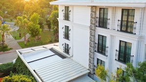 A multi-story building with balconies, a flat roof, and a garden area. - Perast City Hotel (Konyaalti)