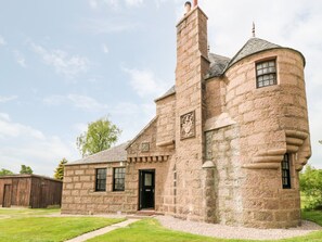 Un edifici de pedra amb una torre i una xemeneia, que presenta una porta i finestres.