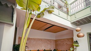 An indoor seating area with wooden furniture and a large potted plant. - Riad Lalla Mimouna (Marrakech)