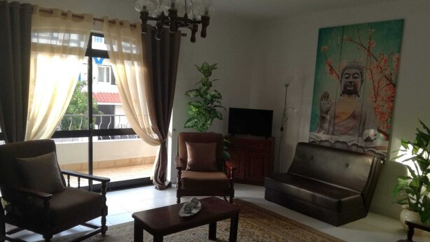 A living room with a sofa, armchairs, a coffee table, a TV, and a Buddha painting. - T3 Vivenda Bemposta / Portimão (Portimão)