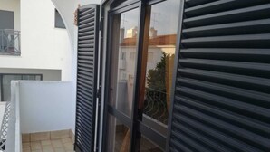 A balcony with a sliding glass door, a tiled floor, and a view of neighboring buildings. - T3 Vivenda Bemposta / Portimão (Portimão)