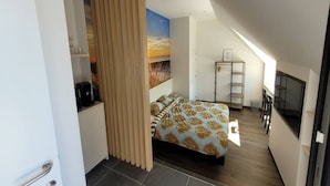 A modern bedroom with a bed, a painting, a desk, and a TV.