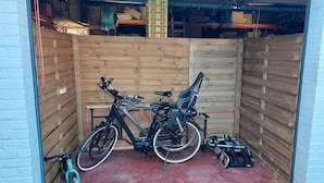 A wooden partitioned area with two bicycles and a tricycle.