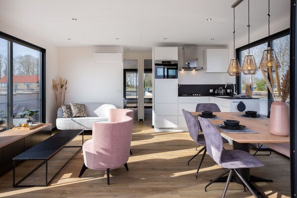 A modern kitchen with a dining area, large windows, and a view of the outside.