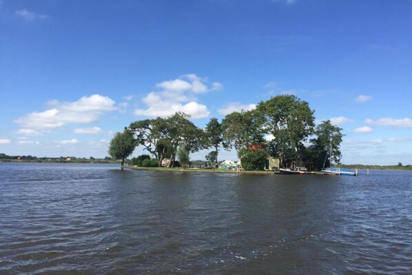 A lakeside property with a dock, trees, and a small building.