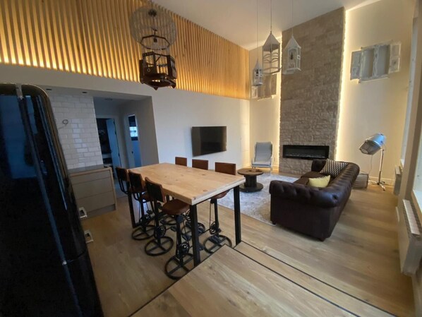 A modern living room with a wooden dining table, black chairs, a dark sofa, and a fireplace. - Nice apartment in the center of Santander (Santander)