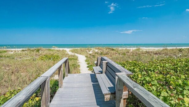 A wooden boardwalk leading to a beach with a clear view of the ocean.